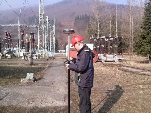 Geodet v prilbe s GNSS prijímačom v areáli rozvodne